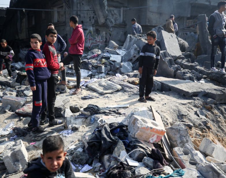 Palestinos estão se reunindo em meio aos escombros de edifícios destruídos após um bombardeio israelense em Deir El-Balah, Faixa de Gaza, em 18 de dezembro de 2023. (Majdi Fathi/NurPhoto via Getty Images)