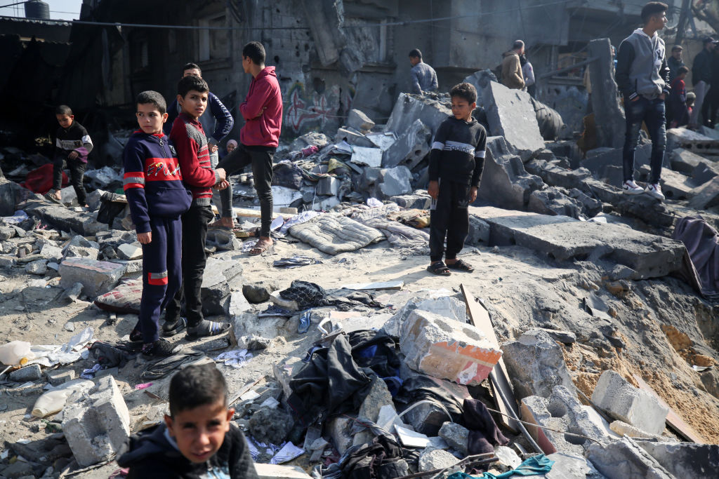 Palestinos estão se reunindo em meio aos escombros de edifícios destruídos após um bombardeio israelense em Deir El-Balah, Faixa de Gaza, em 18 de dezembro de 2023. (Majdi Fathi/NurPhoto via Getty Images)