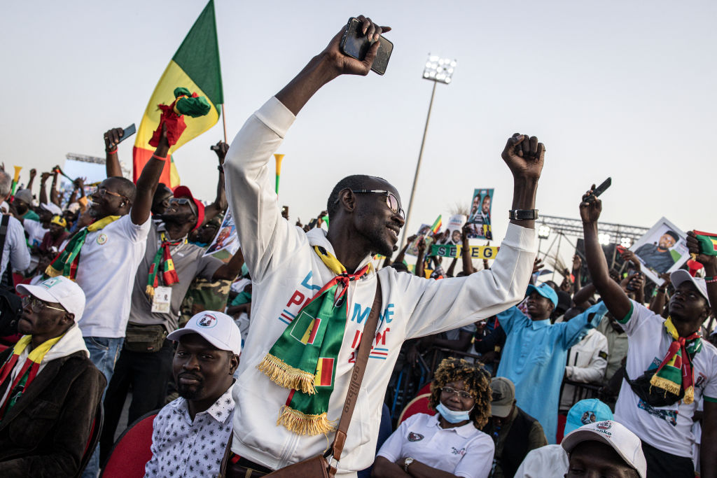 Apoiadores do candidato presidencial da oposição Bassirou Diomaye Faye e do líder da oposição Ousmane Sonko comemoram durante seu último comício de campanha em Mbour, Senegal, em 22 de março de 2024. (John Wessels / AFP via Getty Images)