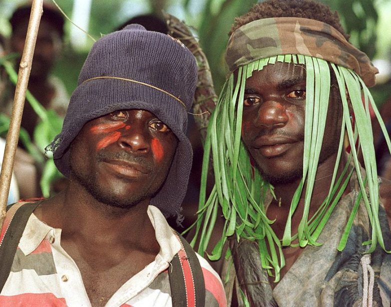 Guerilheiros do Exército Revolucionário de Bougainville, alguns ainda vestindo camuflagem, observam a assinatura do acordo de cessar-fogo que encerrou sua campanha. (Torsten Blackwood / AFP via Getty Images)