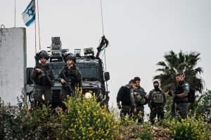 Soldados israelenses monitoram moradores palestinos da Cisjordânia com autorizações condicionais que cruzavam um posto de controle para entrar em Jerusalém e rezar na Mesquita de Al-Aqsa durante o Ramadã, em Qalandia, na Cisjordânia ocupada, na sexta-feira, 29 de março de 2024. (Marcus Yam / Los Angeles Times)