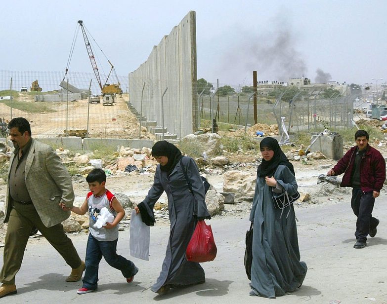 Palestinos caminham pelo posto de controle de Qalandia, nos arredores da cidade de Ramallah, na Cisjordânia, em 6 de maio de 2004. (David Silverman / Getty Images)