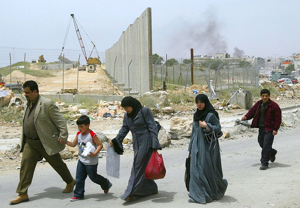 Palestinos caminham pelo posto de controle de Qalandia, nos arredores da cidade de Ramallah, na Cisjordânia, em 6 de maio de 2004. (David Silverman / Getty Images)