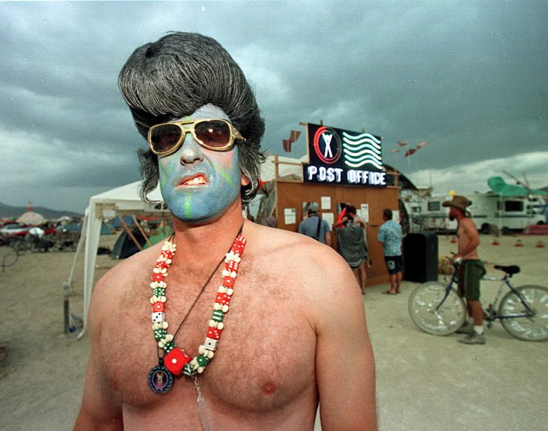 Um participante do Burning Man, de Las Vegas, exibe um sorriso sarcástico usando uma fantasia de Elvis Presley em 6 de setembro de 1998, no Deserto de Black Rock, Nevada. (Mike Nelson / AFP via Getty Images)