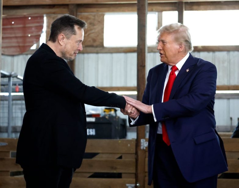 Elon Musk apertando a mão de Donald Trump nos bastidores durante um comício de campanha em 5 de outubro de 2024, em Butler, Pensilvânia. (Anna Moneymaker / Getty Images)