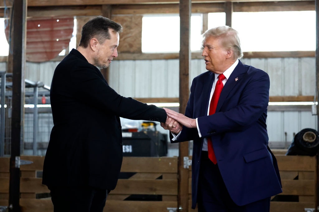 Elon Musk apertando a mão de Donald Trump nos bastidores durante um comício de campanha em 5 de outubro de 2024, em Butler, Pensilvânia. (Anna Moneymaker / Getty Images)